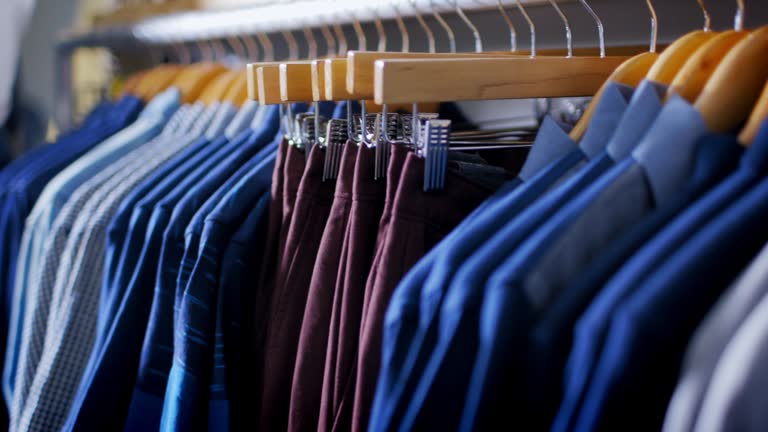 stylish shirts and pants hang from racks in modern clothing store
